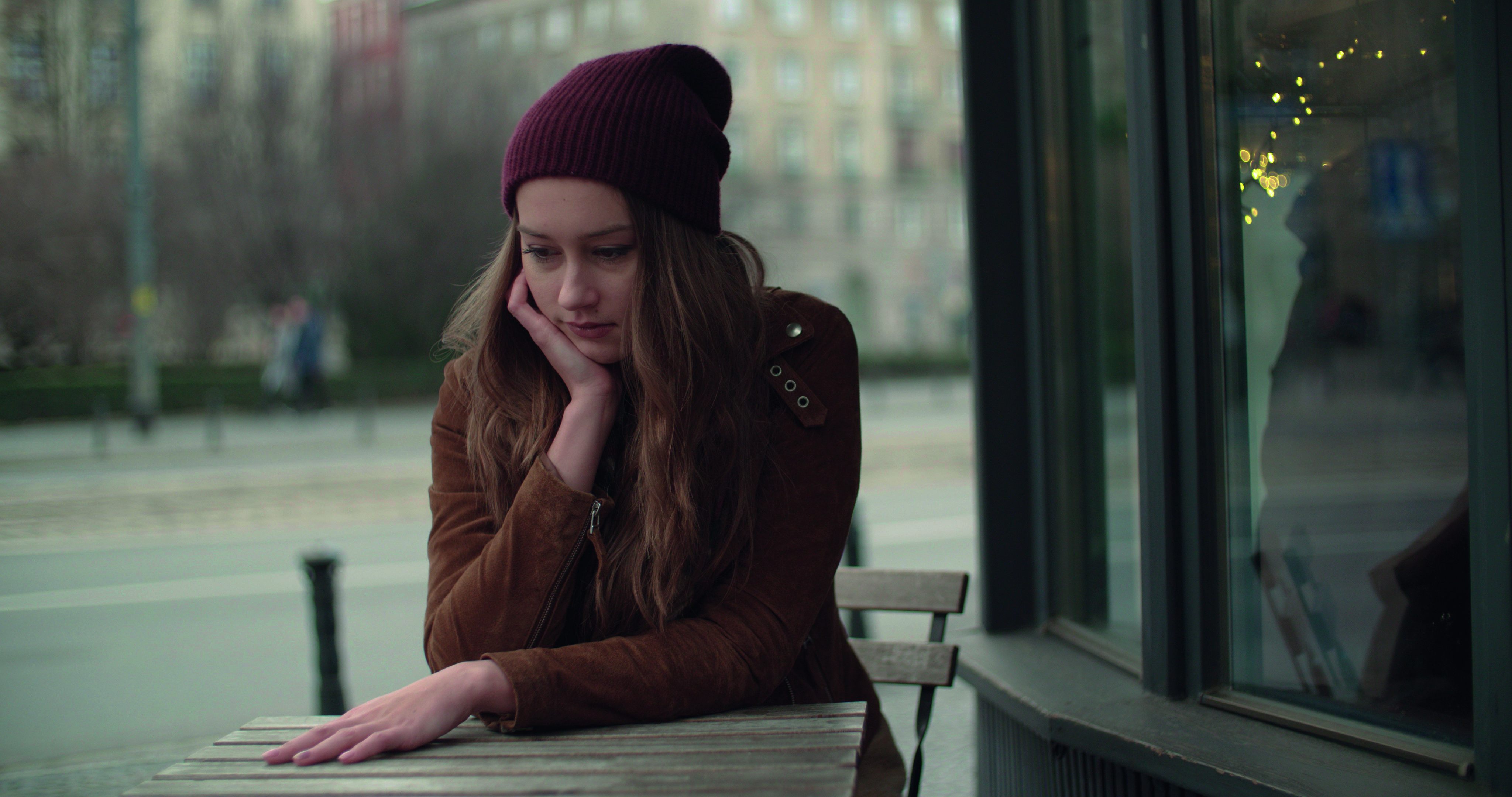 Teenager sitting at a table outside a cafe.
