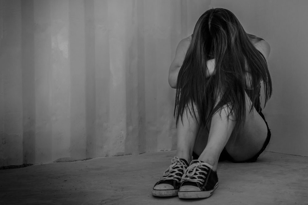 Teenager sitting on the floor with her head to her knees